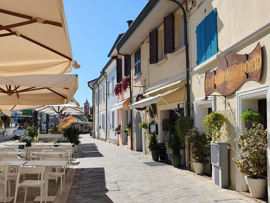 Houses and restaurant tables along the canalside in Cesenatico