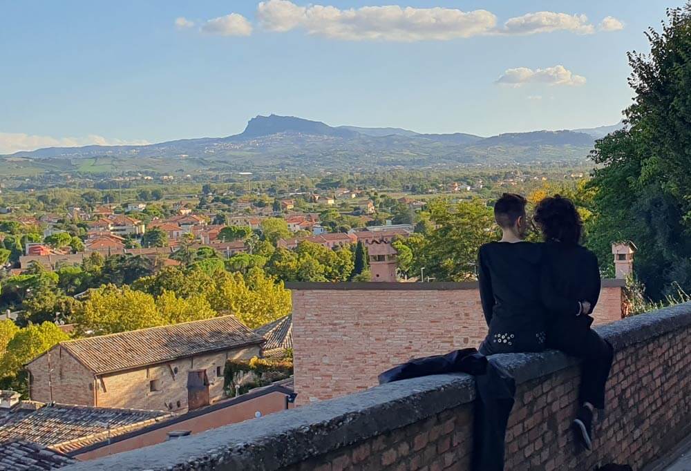 The view from the walls of Santarcangelo di Romagna over rooftops and green plain towards the crag of San Marino