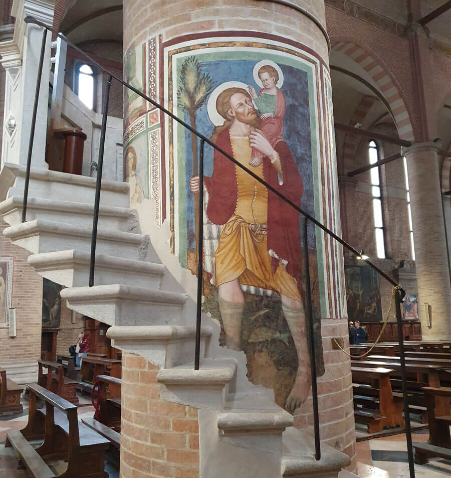 A flight of steps up to a pulpit in front of a fresco of St Christopher carrying Jesus on his shoulder within the church of San Nicolò, Treviso