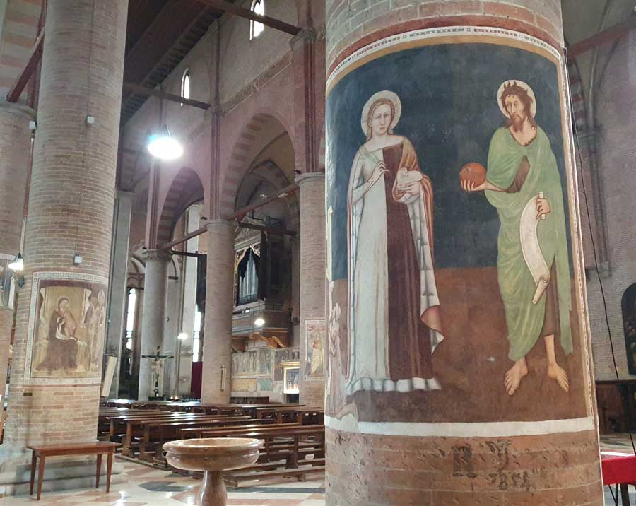 Interior of the church of San Nicolò, with tall columns rising to pointed arches and a fresco in the foreground on a round column