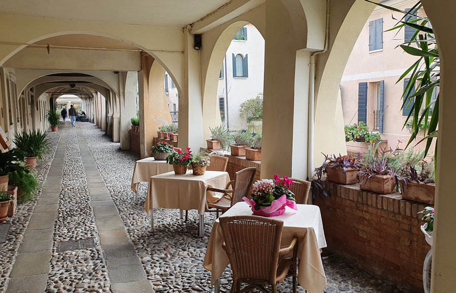 Restaurant tables in a portico overlooking a canal