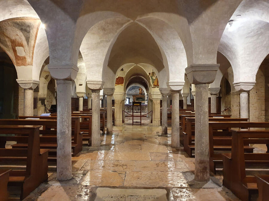 Low-ceilinged crypt space in Treviso's Duomo,with columns,arches and glimpses of fresco